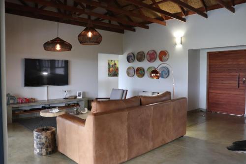 a living room with a brown couch and a tv at MANZINI RIVER HOUSE - Mjejane Private Game Reserve, Greater Kruger National Park in Hectorspruit