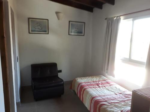 a bedroom with a chair and a bed and a window at Maraja1 in Mar de Ajó