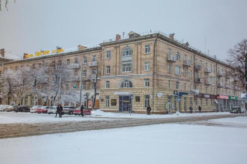 a large brick building on a snow covered street at Optima Cherkasy Hotel in Cherkasy
