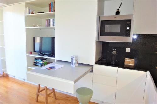 a white kitchen with a desk and a tv at Porto Sunny Terrace Almada in Porto