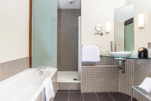 a bathroom with a tub and a sink at Best Western Plus Le Canard sur le Toit in Colomiers