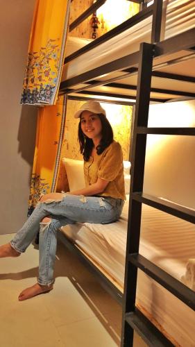 a woman sitting on top of a bunk bed at OK CHIC PHUKET HOSTEL in Phuket Town