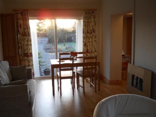 sala de estar con mesa, sillas y ventana en Ty'r Afon - River Cottage, en Bala