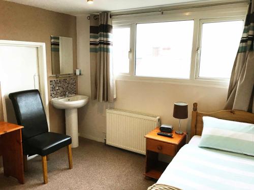 a bedroom with a bed and a sink and a chair at Esk Vale Guest House in Portsmouth