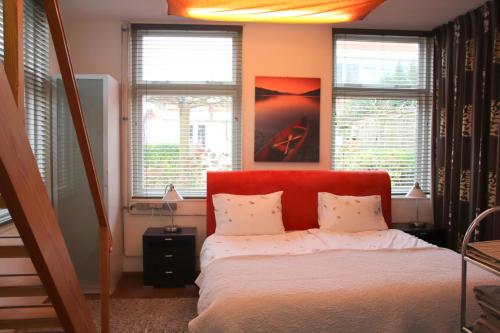 Colijnsplaatにあるhet Bakkershuisjeのベッドルーム1室(赤いヘッドボードと窓付きのベッド1台付)