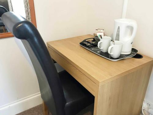 a wooden table with a chair and a tray with cups at Esk Vale Guest House in Portsmouth