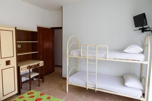 a room with three bunk beds and a desk at Appartamenti Padoan in Sottomarina