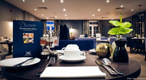 a table with plates and utensils in a restaurant at Donnington Grove in Newbury