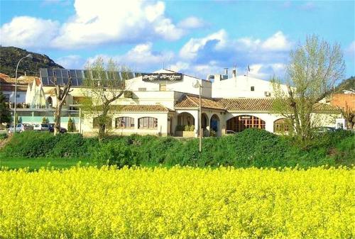 a large white house with a field of yellow flowers at Hotel Rural Jaumet in Torá de Rulbregos