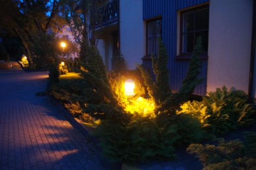 a lit up garden in front of a house at night at Guest House Vasara in Nida