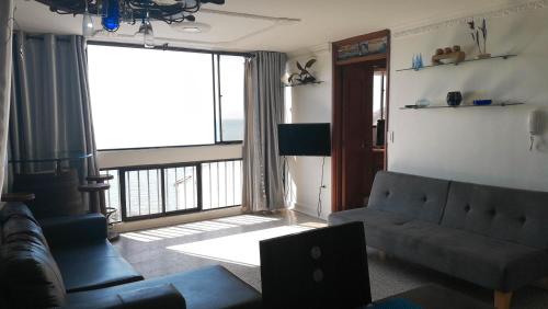 Apartamentos Osma في سانتا مارتا: غرفة معيشة مع أريكة ونافذة كبيرة