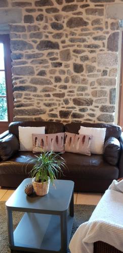a living room with a couch and a stone wall at Gite De La Tannerie 2 in Dinan