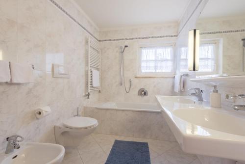 a white bathroom with a tub and a sink and a toilet at Residence Diamant in Castelrotto
