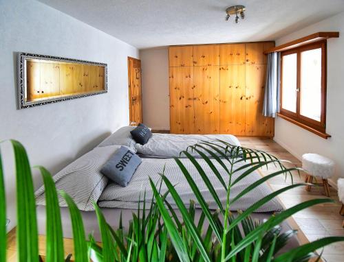 ラアにあるLakeside - 3.5 Zimmer Ferienwohnung am Laaxerseeの植物のある部屋のベッド1台が備わるベッドルーム1室を利用します。