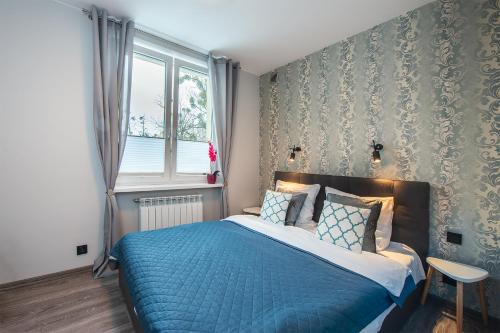 sypialnia z niebieskim łóżkiem i oknem w obiekcie Apartament Manufaktura w Łodzi
