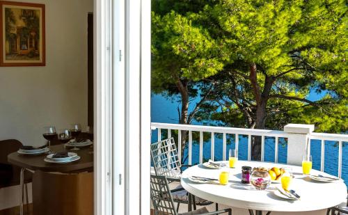 een tafel en stoelen op een balkon met uitzicht op de oceaan bij Apartments Velo Lago in Lastovo