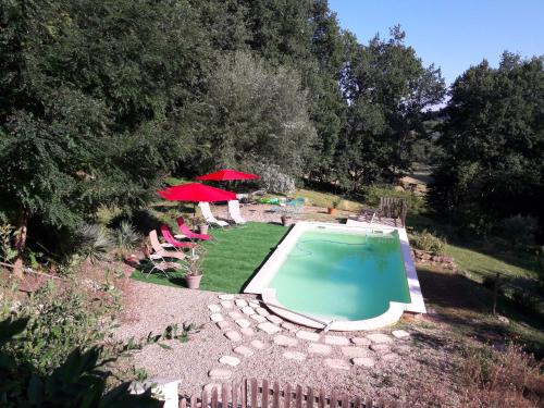 a swimming pool in a yard with chairs and umbrellas at la clairiere in Sarlat-la-Canéda