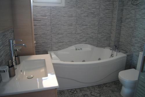 a white bath tub in a bathroom with a toilet at Calypso Apartments in Vathi, Ithaka
