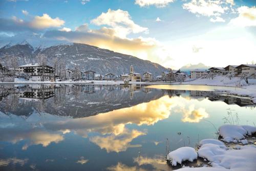 a lake covered in snow with houses and mountains at Lakeside - 3.5 Zimmer Ferienwohnung am Laaxersee in Laax
