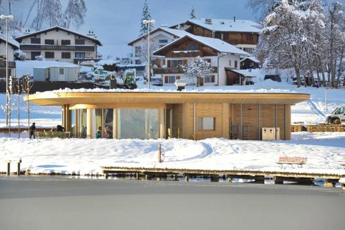 a house in the snow next to a body of water at Lakeside - 3.5 Zimmer Ferienwohnung am Laaxersee in Laax
