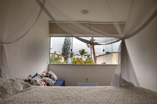 a bedroom with a bed and a large window at Casa Praia Pitinga in Arraial d'Ajuda