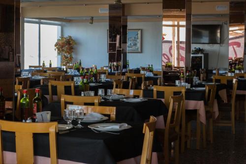 un comedor lleno de mesas y sillas con botellas de vino en Hotel Pepa, en Villafranca de Ebro