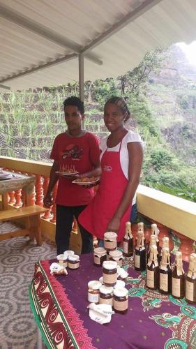 a man and a woman standing next to a table with bottles of wine at casa xoxo in Ribeira Grande