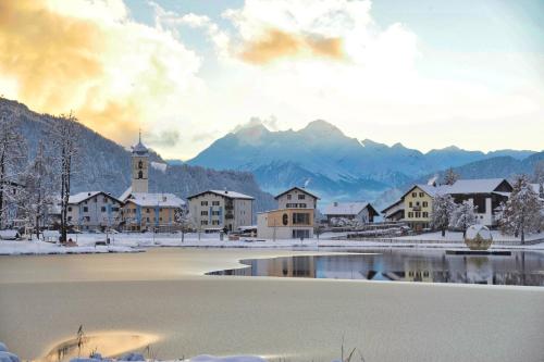 a town in the snow with a lake and a church at Casa al Lag - direkt am Laaxersee in Laax