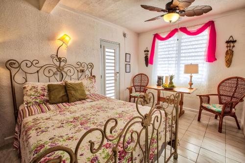 een slaapkamer met een bed en stoelen en een plafondventilator bij Coconut Palms Inn in Rincon