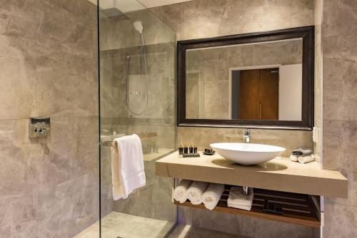 a bathroom with a sink and a glass shower at Distinction Christchurch Hotel in Christchurch