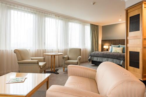 a hotel room with a bed and a couch and chairs at Distinction Christchurch Hotel in Christchurch