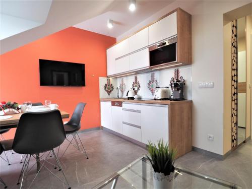 a kitchen with an orange accent wall and a table at VIP Apartamenty Stara Polana 2 in Zakopane