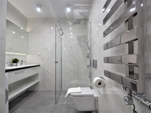 a white bathroom with a shower and a toilet at VIP Apartamenty Stara Polana 2 in Zakopane