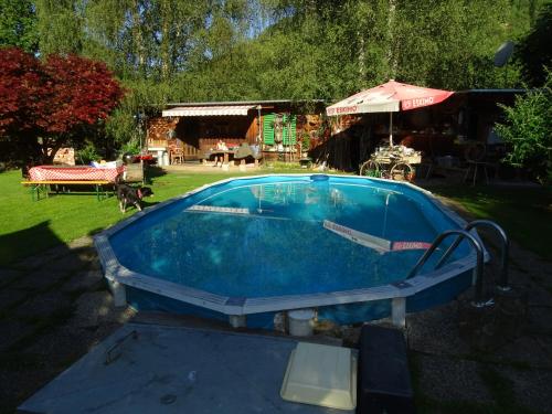 a swimming pool in a yard with a table and an umbrella at Ferienhaus-Römerthurm in Schöder