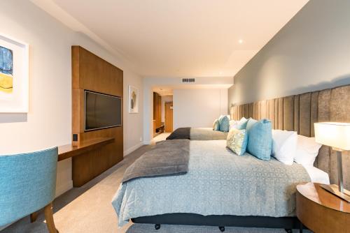 a bedroom with two beds and a flat screen tv at Distinction Christchurch Hotel in Christchurch