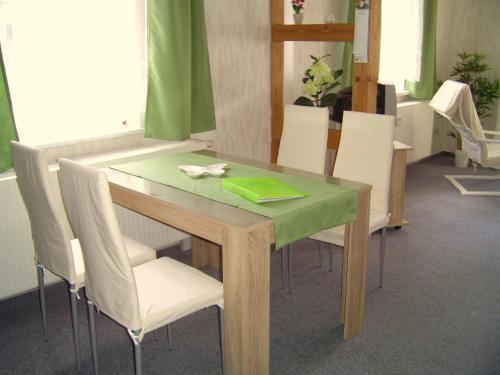 a dining room table with white chairs and a green table at Ferien-/ Monteurwohnung Nette in Themar