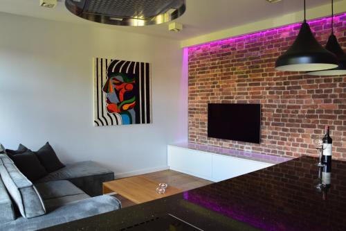 een woonkamer met een bakstenen muur met paarse verlichting bij Szopienicka Luxury in Katowice