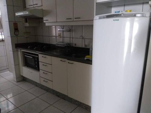 a kitchen with white cabinets and a refrigerator at Apartamento Meia Praia - 140 metros do mar in Itapema