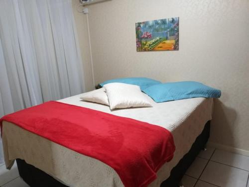 a bed with a red and blue blanket on it at Apartamento Meia Praia - 140 metros do mar in Itapema