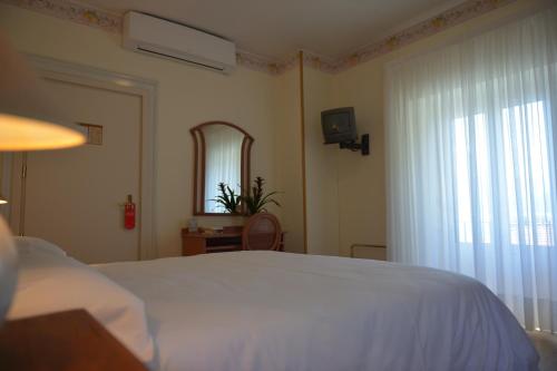 a bedroom with a white bed and a window at Villa Belvedere Como Lake Relais in Argegno