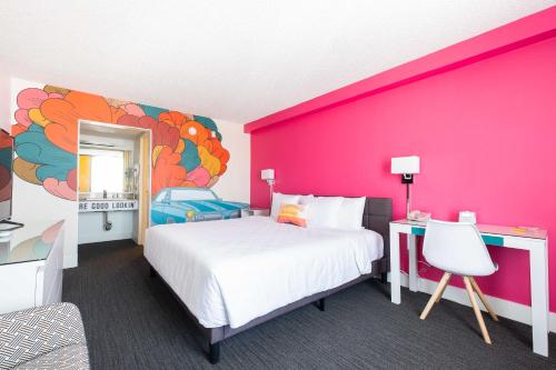 a bedroom with a large bed and a pink wall at Rambler Motel in Chula Vista