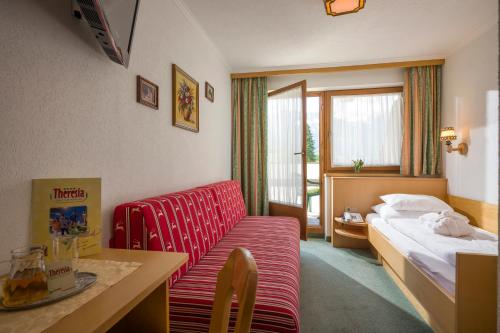 pokój hotelowy z czerwoną kanapą i łóżkiem w obiekcie Hotel Theresia w mieście Ramsau im Zillertal