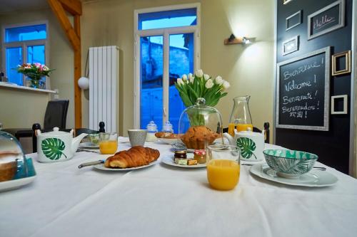 Una mesa con alimentos para el desayuno y jugo de naranja sobre ella. en Le Nid Cosy Bordeaux, en Burdeos