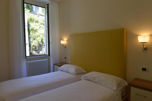 two beds in a room with a window at Villa Belvedere Como Lake Relais in Argegno