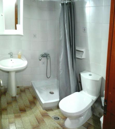 a white bathroom with a toilet and a sink at Hause Zorbas in Paralia Dionysiou
