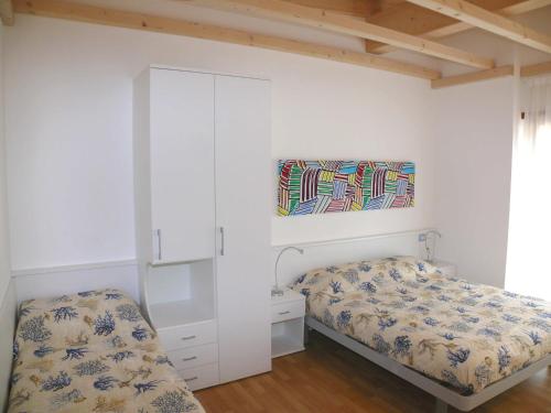 a bedroom with two beds and a cabinet at Bibione Mastervillage in Bibione