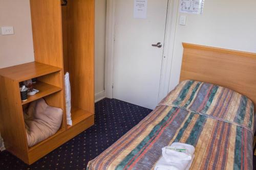 a small bedroom with a bed and a book shelf at Gardners Inn Hotel in Blackheath
