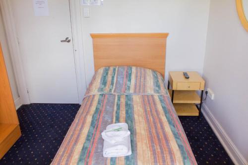 a small bed with a white shoe on top of it at Gardners Inn Hotel in Blackheath