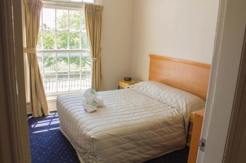 a bedroom with a bed with a teddy bear on it at Gardners Inn Hotel in Blackheath