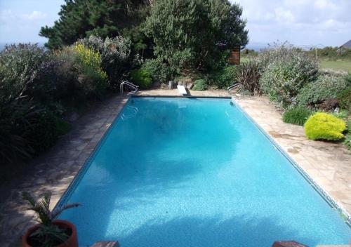 una gran piscina azul en un jardín en The Old Forge B&B, en Sark